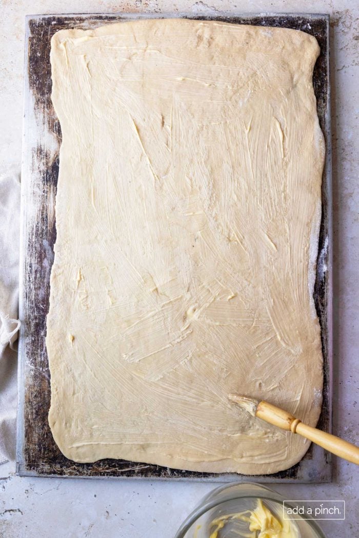 Image of rolled yeast dough with softened butter spread on top.