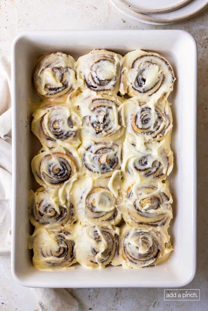 Overhead photo of cinnamon rolls with cream cheese frosting in a white baking dish.