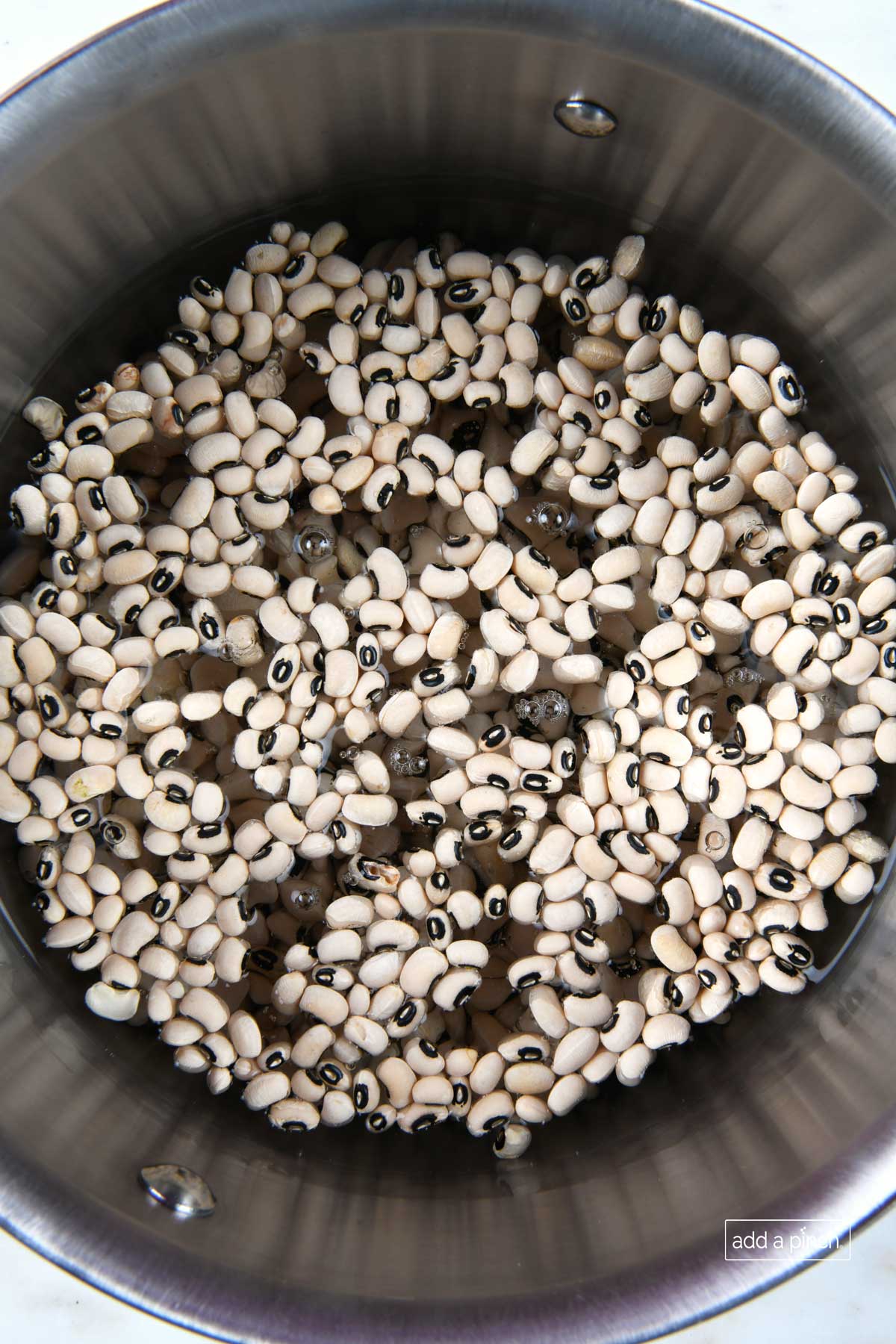 Black eyed peas soaking in water in a large pot.