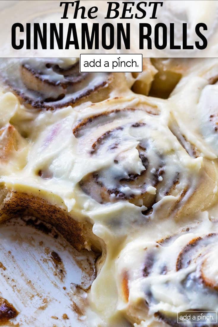Baking dish with cinnamon rolls iced in cream cheese frosting - with text - addapinch.com