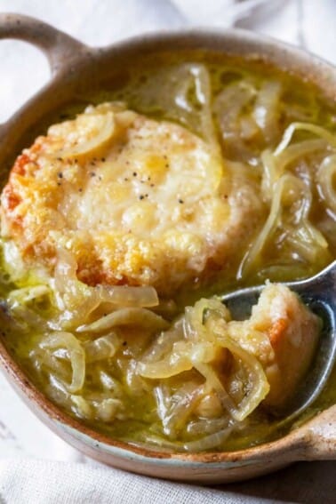 Bowl of French Onion Soup with a spoon filled ready for a bite.