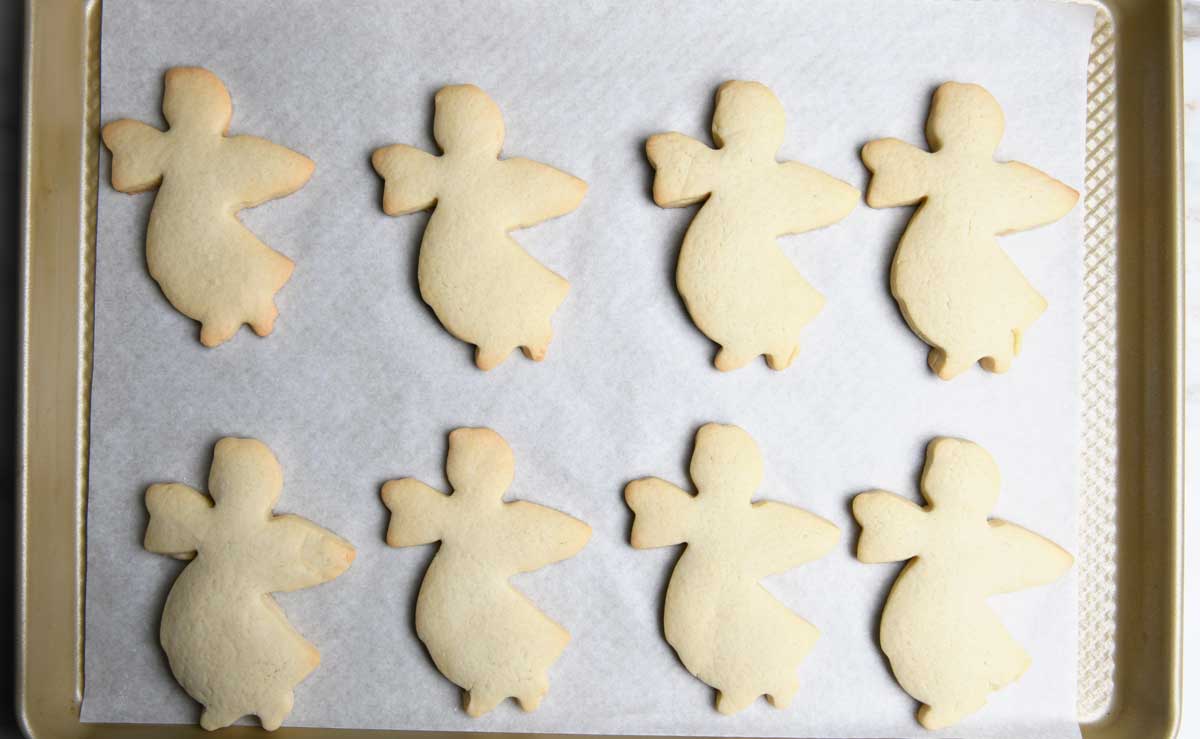 Angel shaped baked sugar cookies on a parchment-lined baking sheet  ready to be decorated.