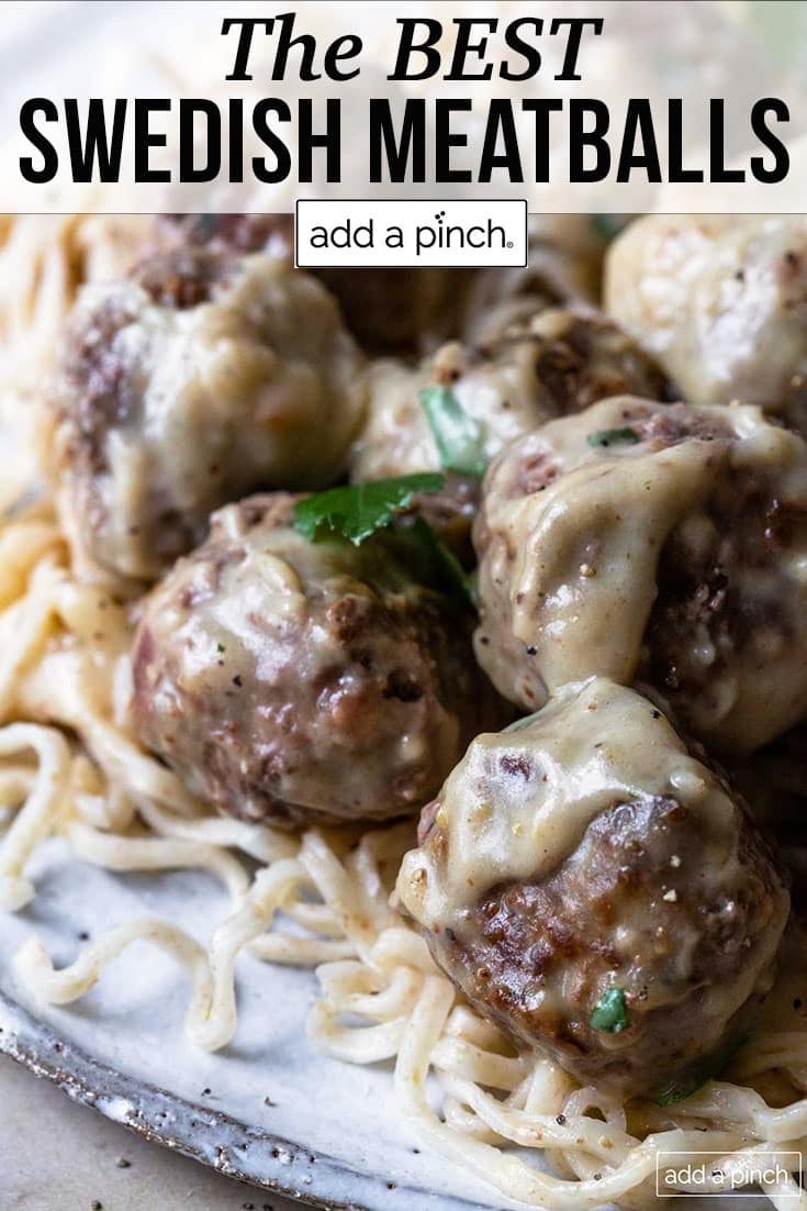 Plate of Swedish meatballs covered in it's own gravy and herbs on top of pasta - with text - addapinch.com