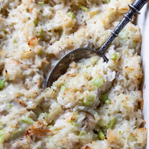 Photo of chicken and rice casserole in a baking dish with a spoon.