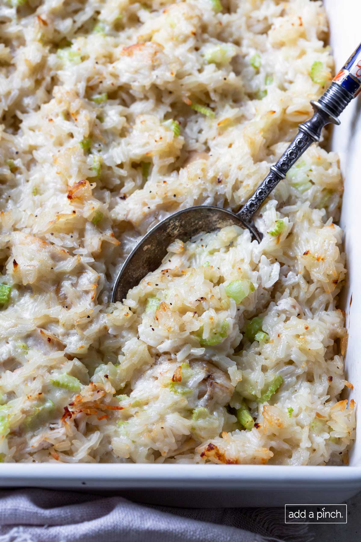 Photo of chicken rice casserole in a baking dish with a spoon ready for serving.