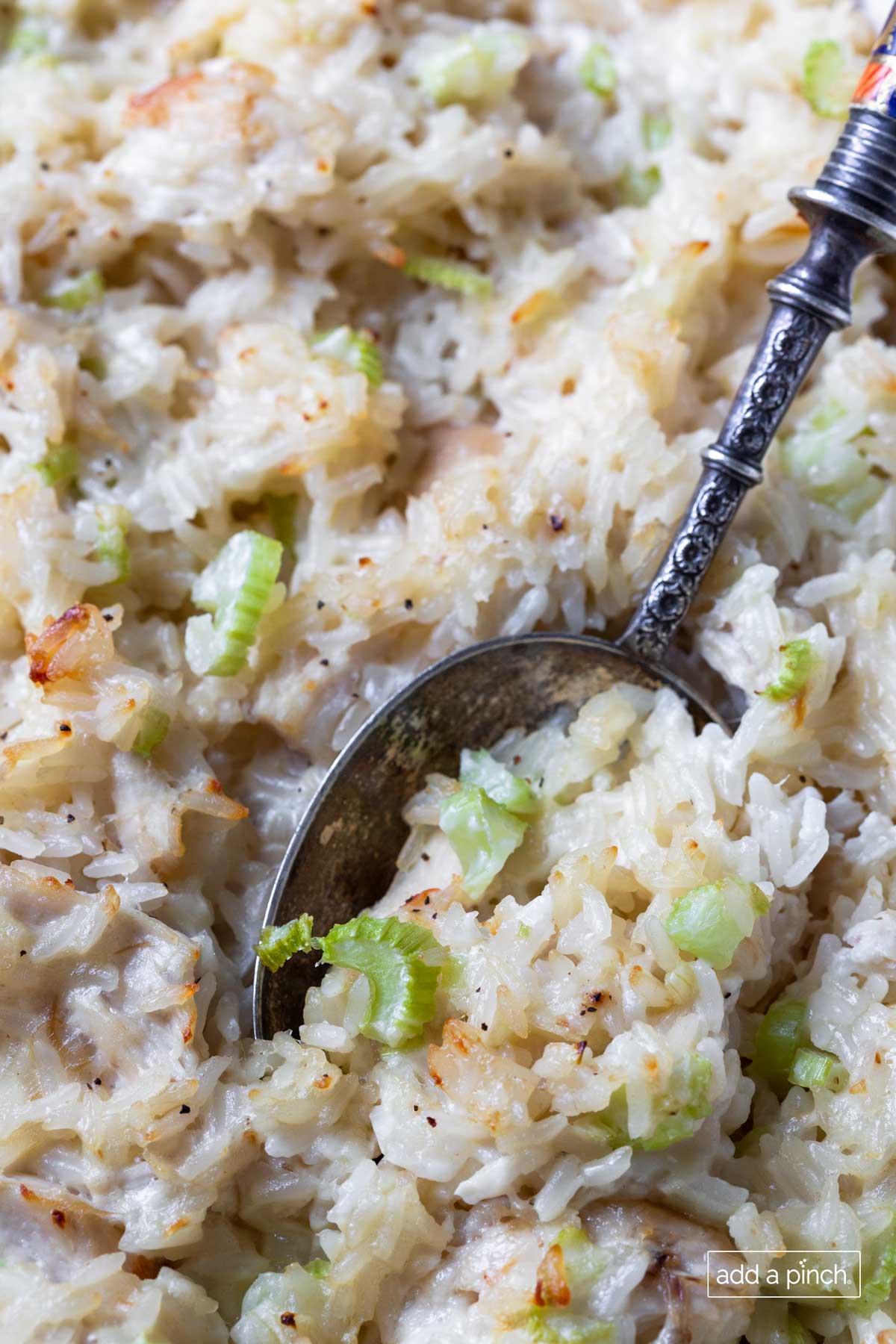 Closeup photograph of spoon filled with chicken and rice casserole with celery and onions.