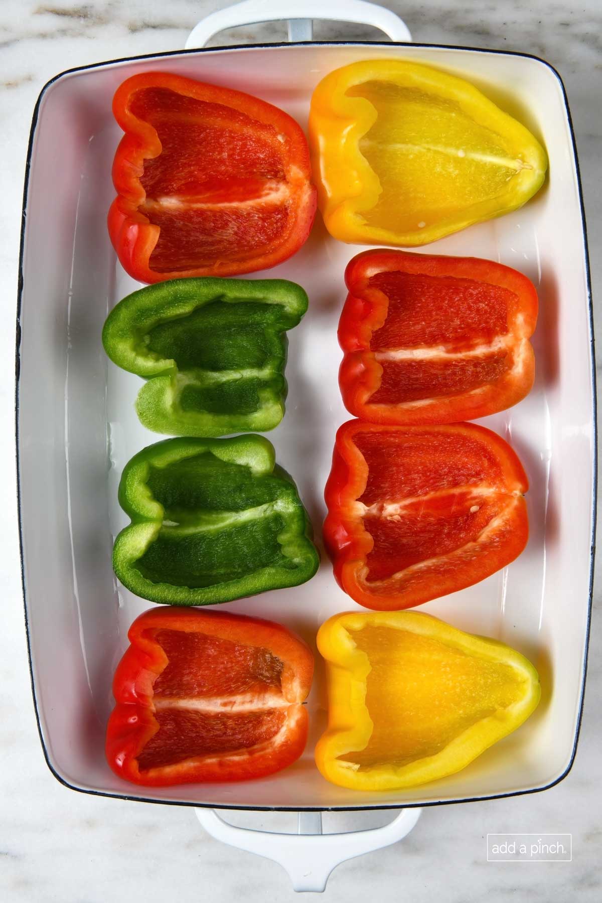 Bell peppers cut lengthwise with the seeds and membrane removed in a baking dish.