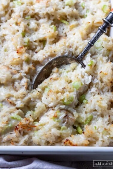 Photo of chicken and rice casserole in a baking dish with a spoon.