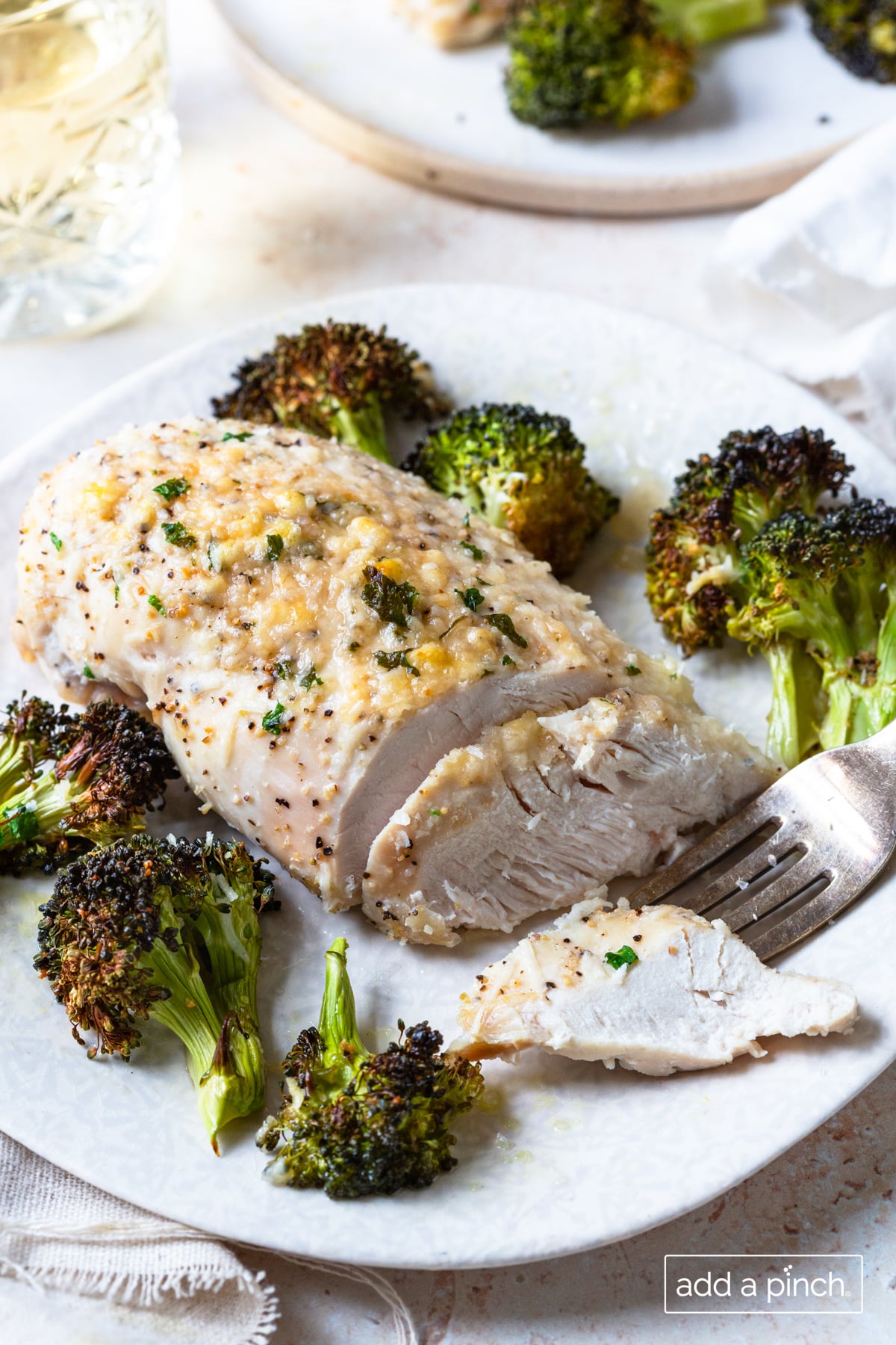 Photo of parmesan crusted chicken and broccoli on a white plate.