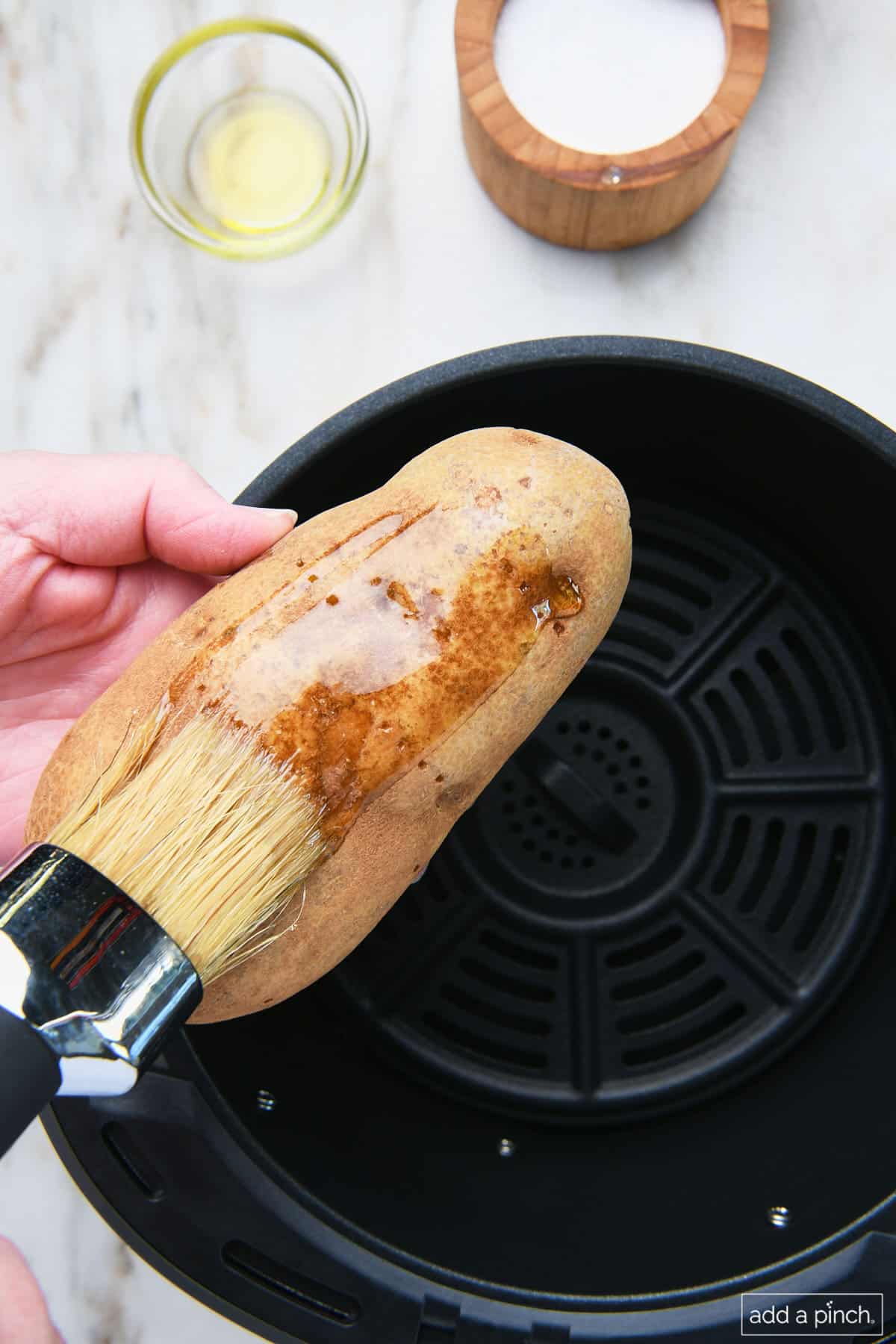 Brushing olive oil onto potato.
