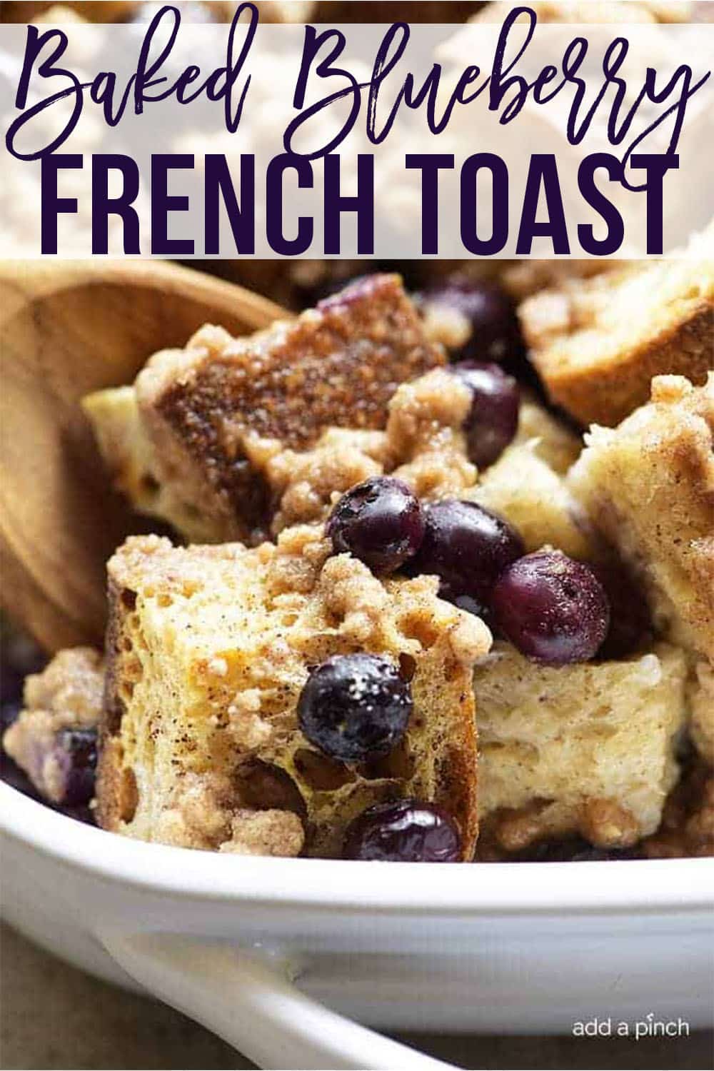 Wooden spoon in white dish of baked blueberry french toast - with text - addapinch.com