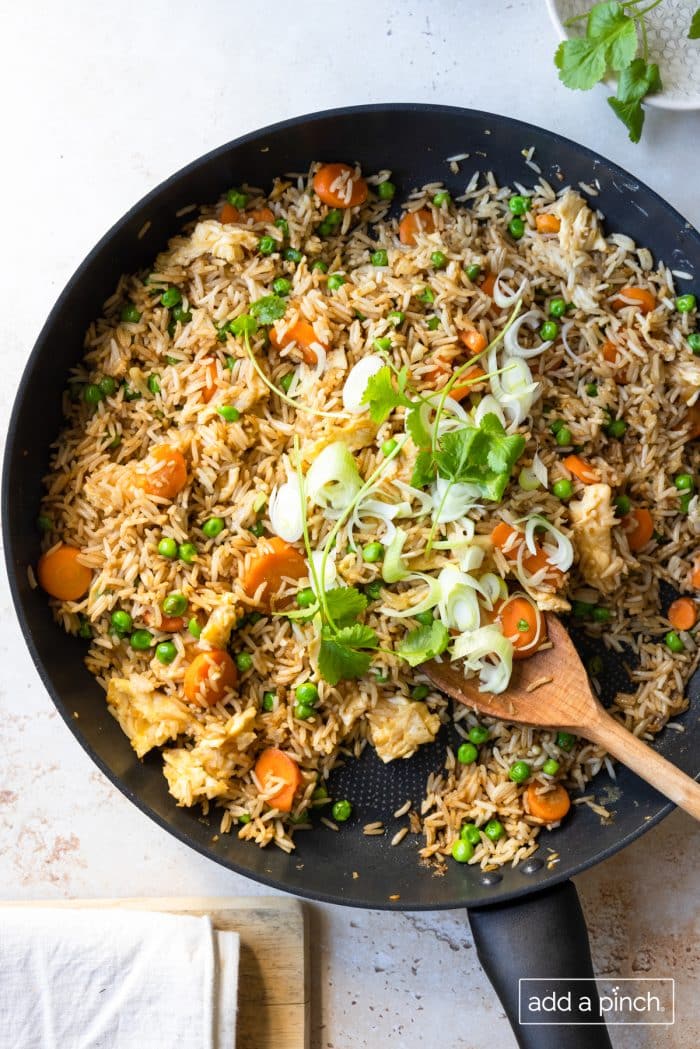 Photo of fried rice in a skillet with green onions and cilantro.