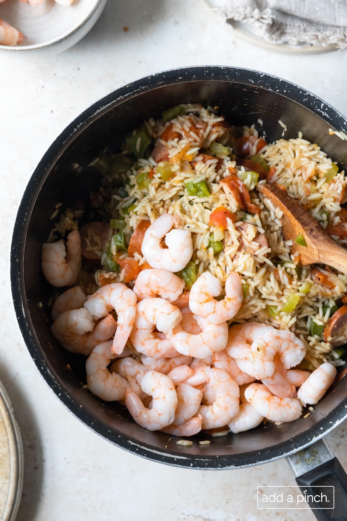 Add shrimp to rice, vegetables and sausage in a pot.