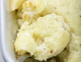 Photo of baked grits casserole in a baking dish on a marble surface.