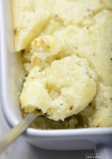 Photo of baked grits casserole in a baking dish on a marble surface.
