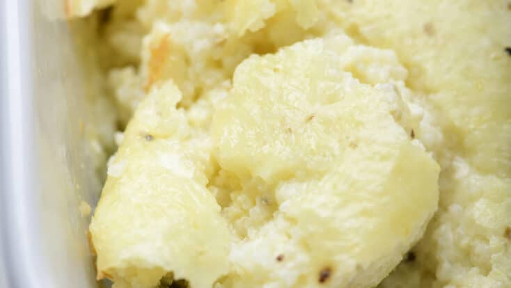 Photo of baked grits casserole in a baking dish on a marble surface.