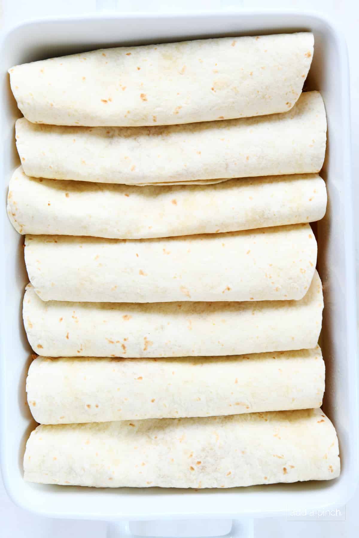 Enchiladas in a white baking dish.