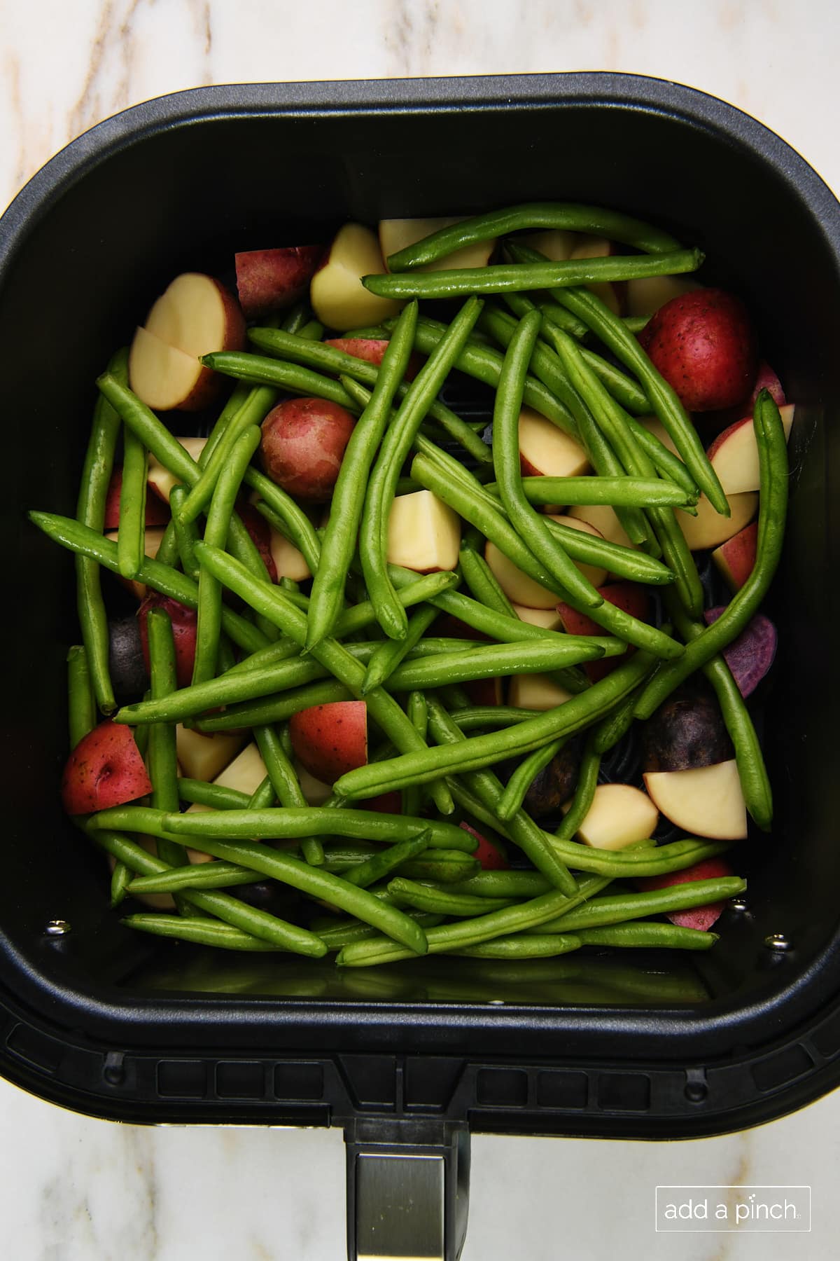 Green beans and potatoes in air fryer basket 