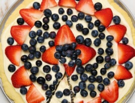 Photo of fruit pizza with a slice for serving.