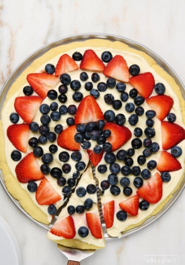 Photo of fruit pizza with a slice for serving.
