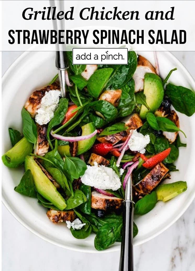 Salad with grilled chicken, strawberries, avocado, onions, cheese in a white bowl - with text - addapinch.com
