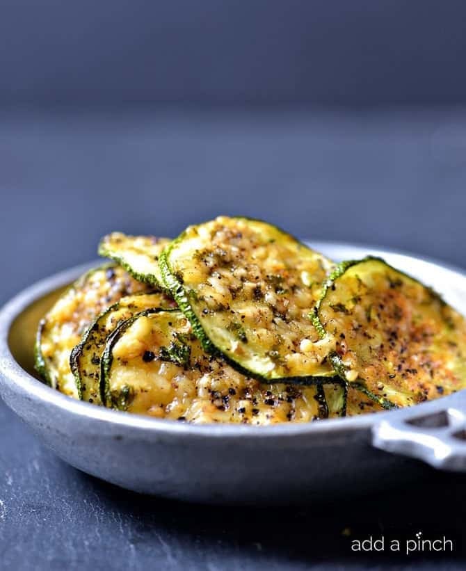 Crisp zucchini chips with parmesan and spices served in a pewter dish - addapinch.com