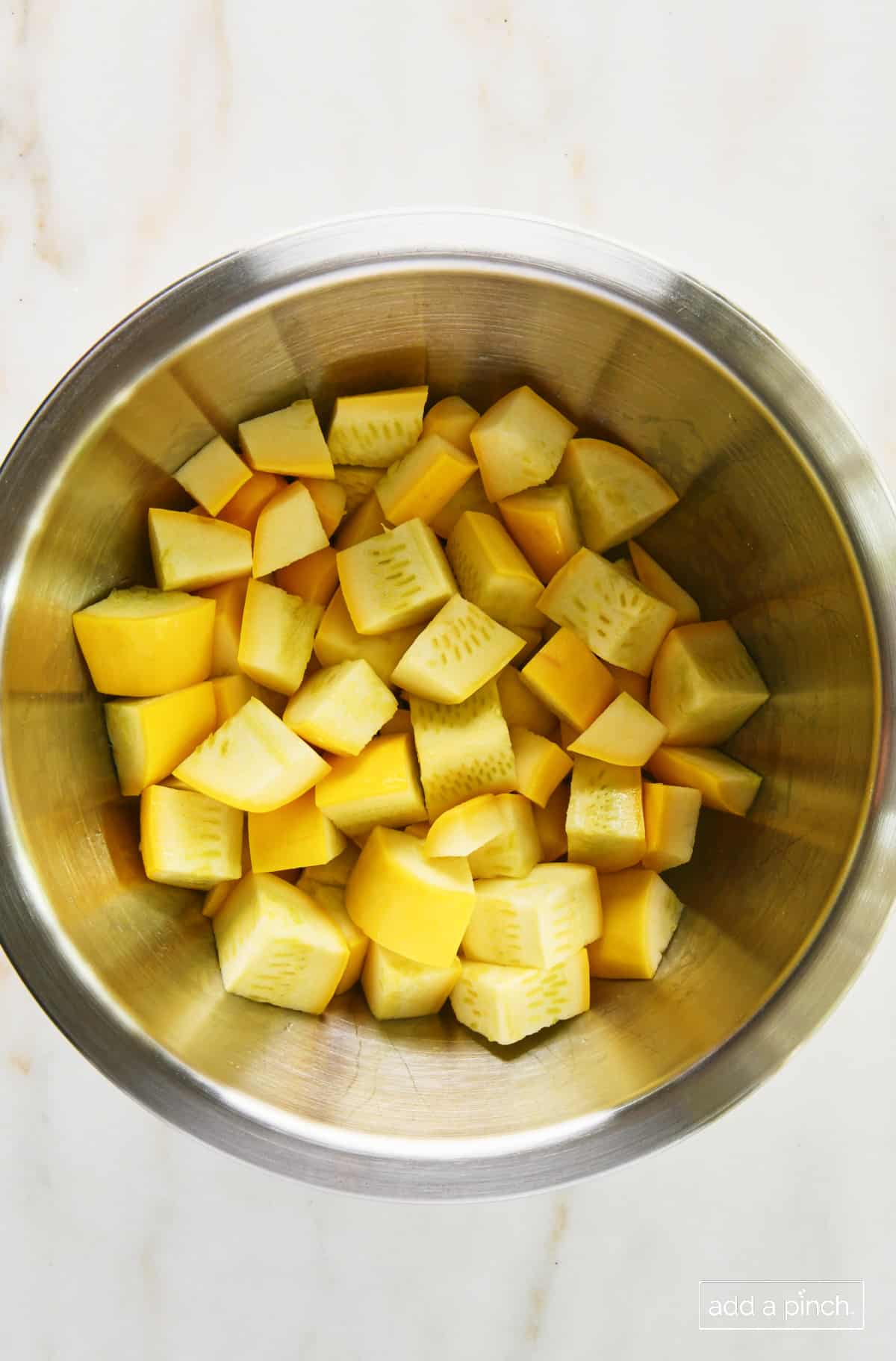 Cut yellow squash in a mixing bowl.