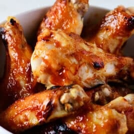 Photograph of bbq chicken wings in a white bowl.