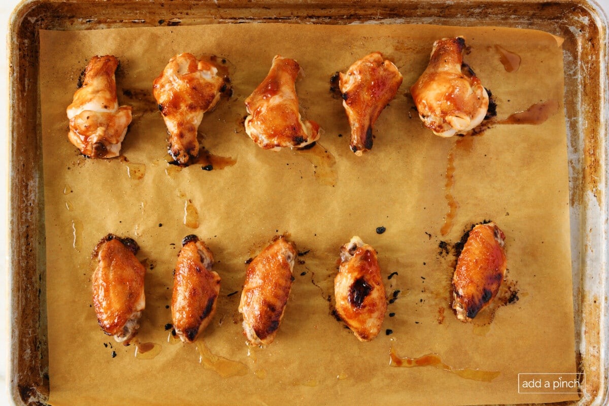 Cooked chicken wings on a parchment lined baking sheet.