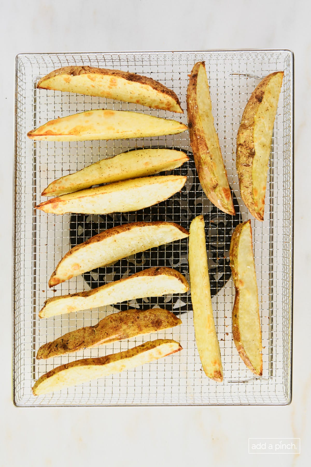 Crispy air fryer potato wedges on a air fryer basket.