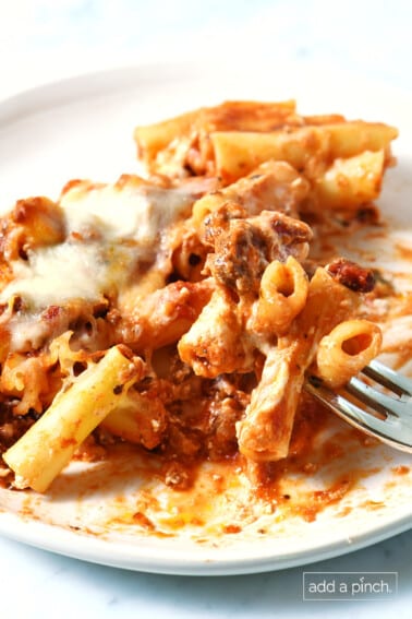 Baked ziti on a white plate with a bite on a fork.