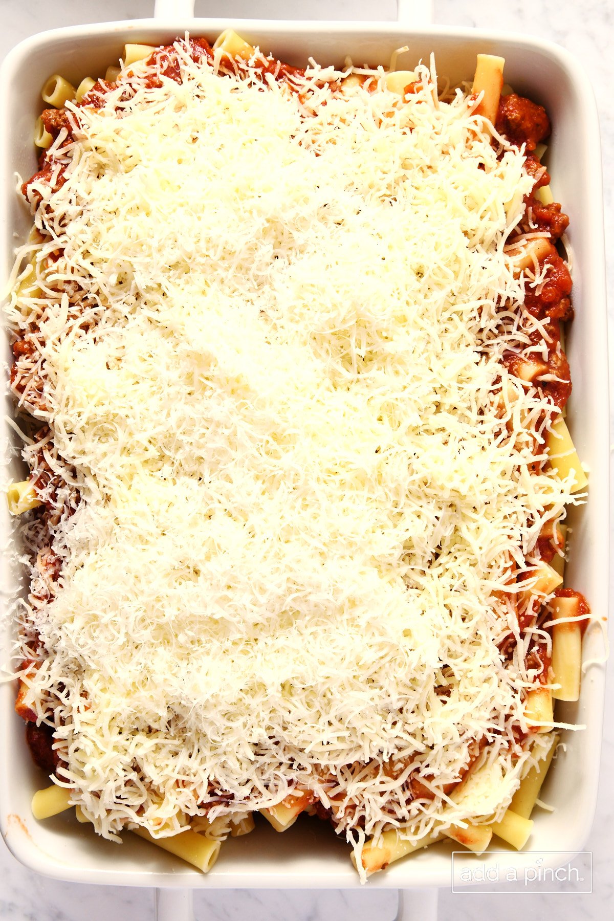 Top the second layer of ziti and meat sauce with cheese.
