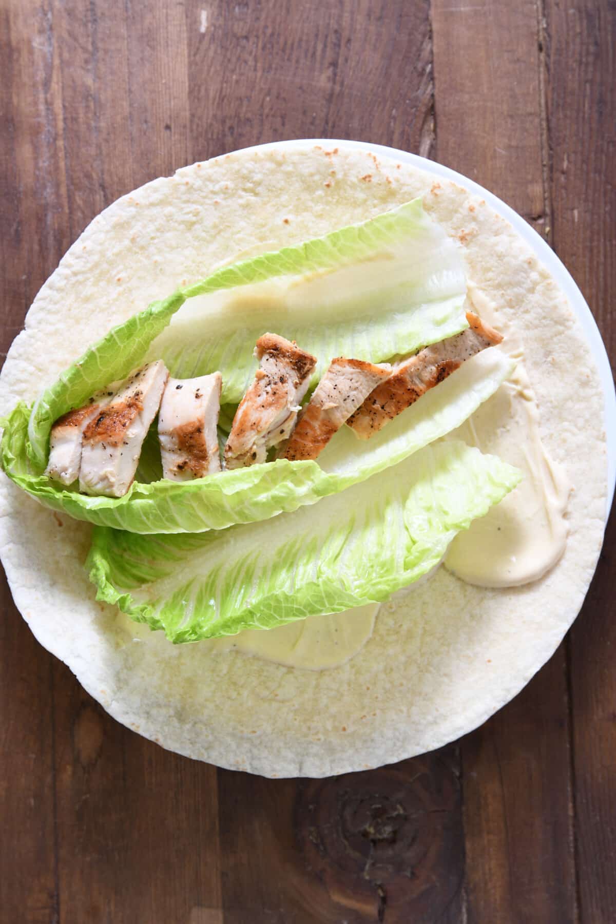Tortilla with ingredients for a chicken caesar salad wrap