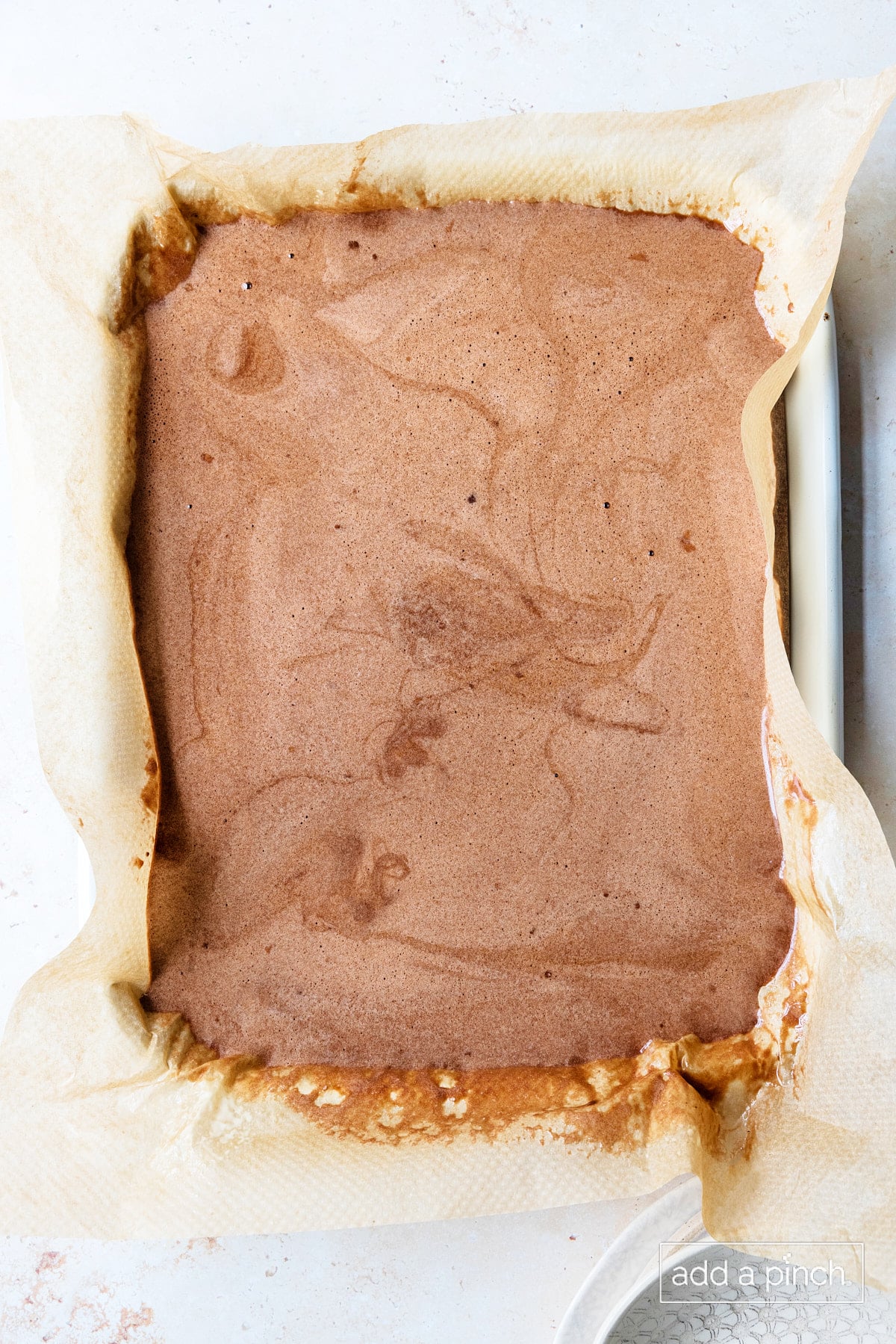 Cake batter poured into a parchment lined baking sheet.