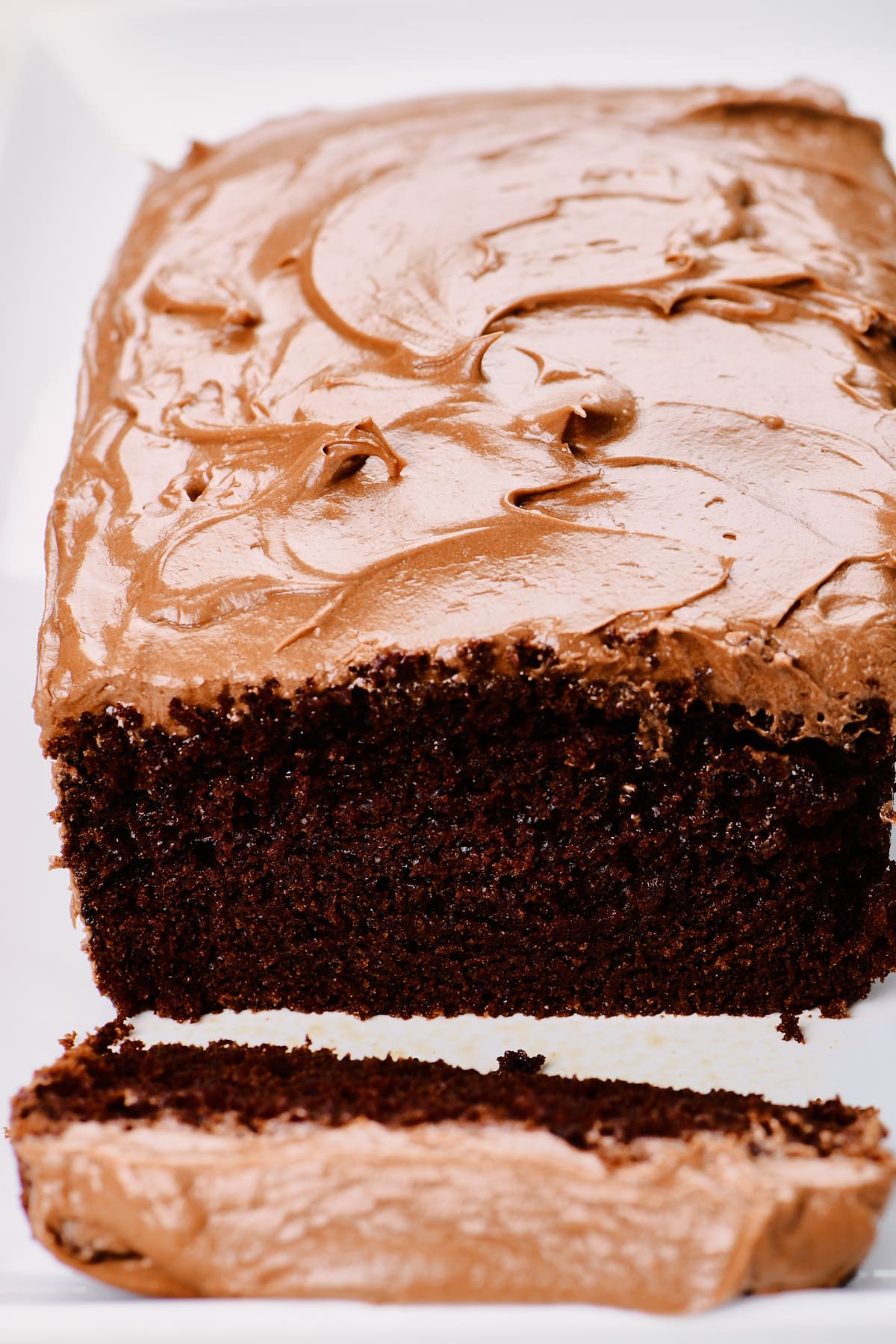 Chocolate loaf cake with chocolate frosting on a white platter.