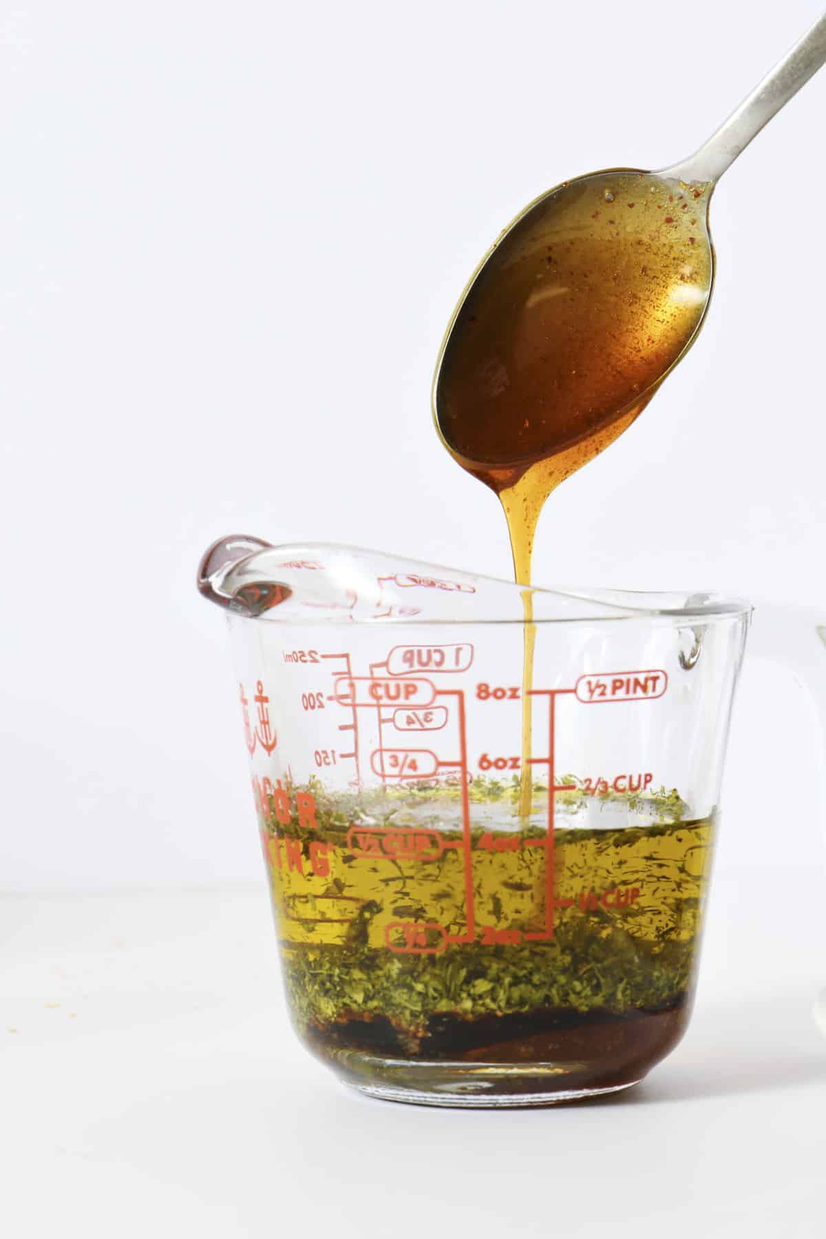 Spicy marinade for crackers in a glass measuring cup with a spoon.