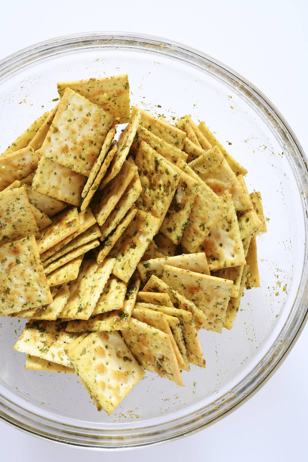 Saltine crackers coated with a spicy ranch marinade in a glass mixing bowl