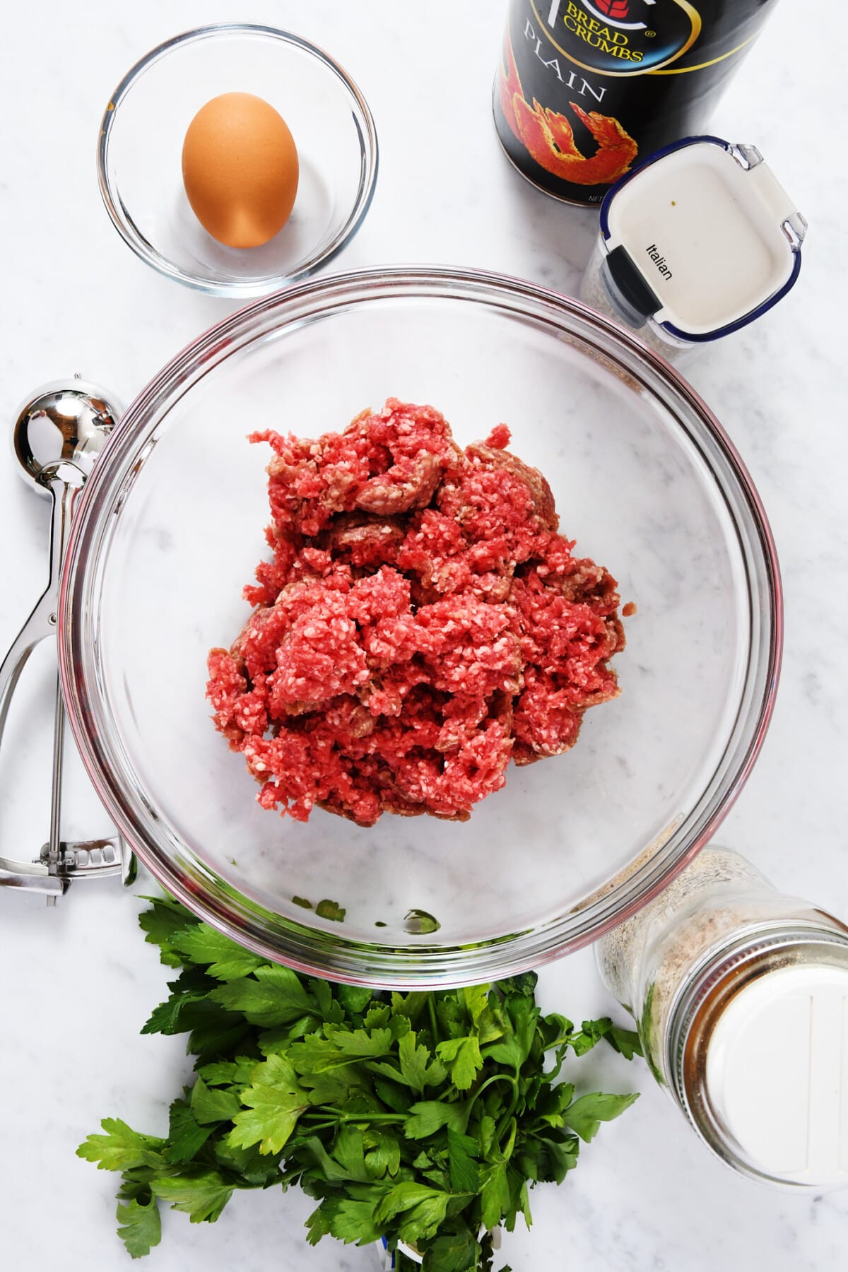 Ingredients used to make homemade meatballs on a marble surface.