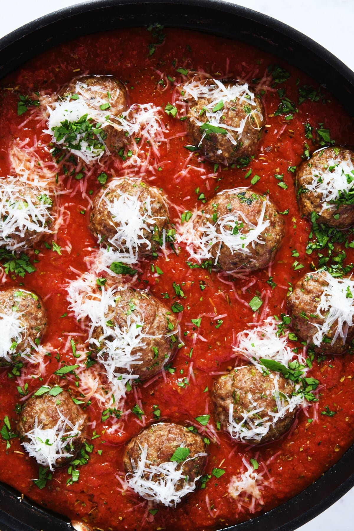 Meatballs in marinara sauce in skillet.