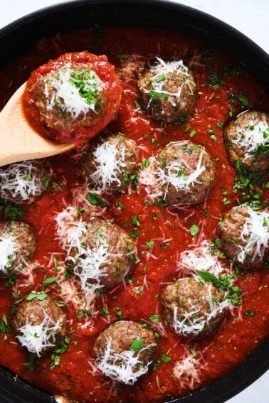 Meatballs in marinara sauce topped with parmesan cheese and parsley.