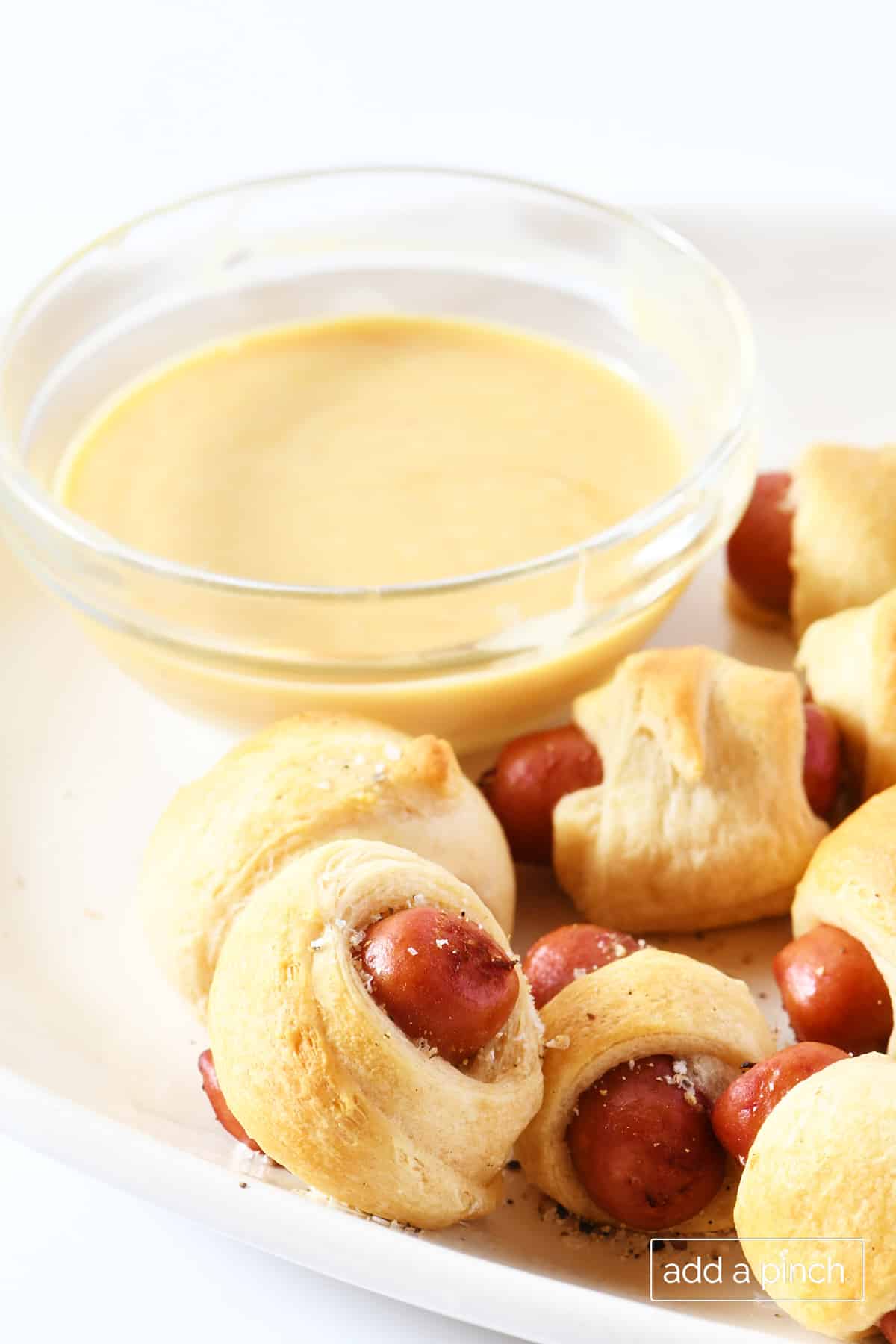 Platter of pigs in a blanket appetizer with honey dijon dipping sauce.