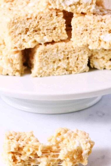 Rice cereal treats on a white bake plate with one in front.