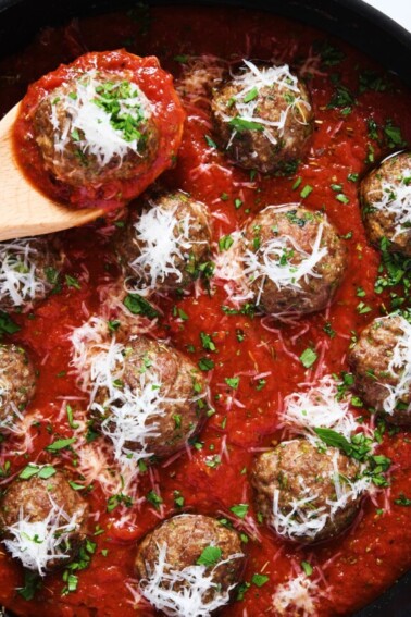 Meatballs in marinara sauce topped with parmesan cheese and parsley.
