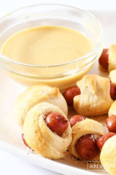Platter of pigs in a blanket appetizer with honey dijon dipping sauce.