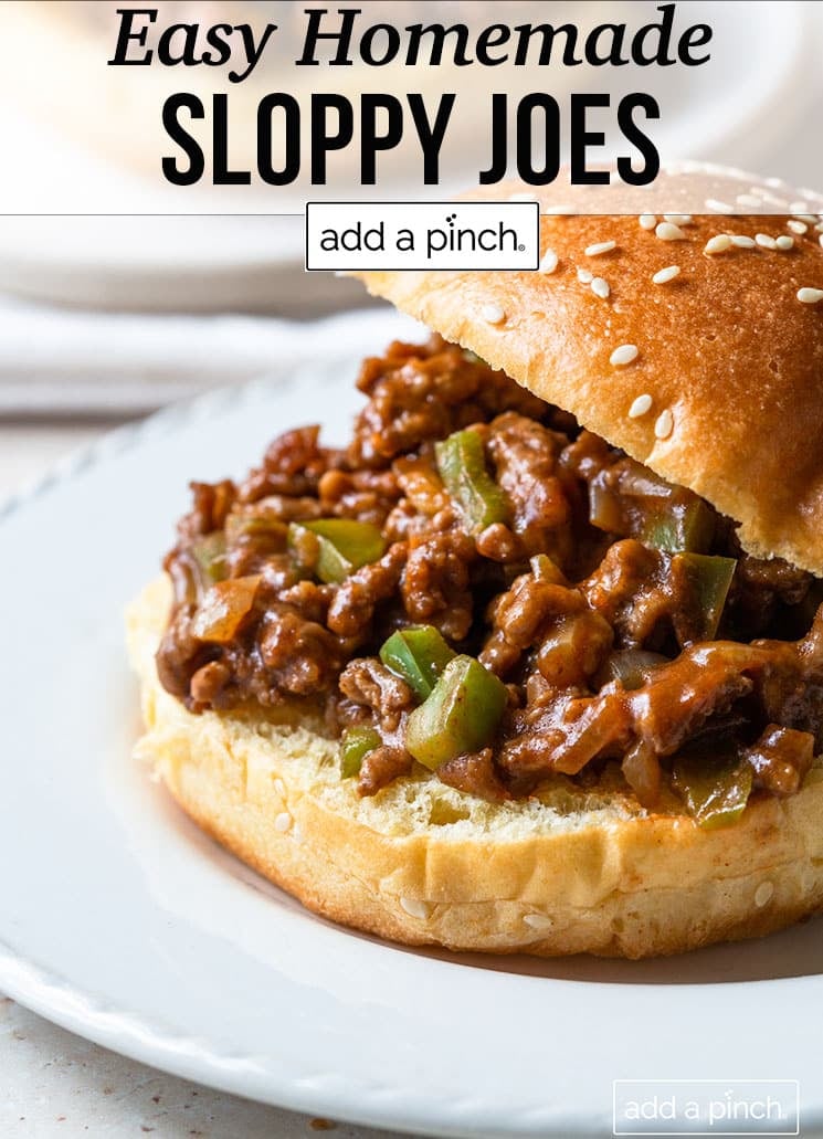 White plate holds Sloppy Joe on sesame seed bun - with text - addapinch.com