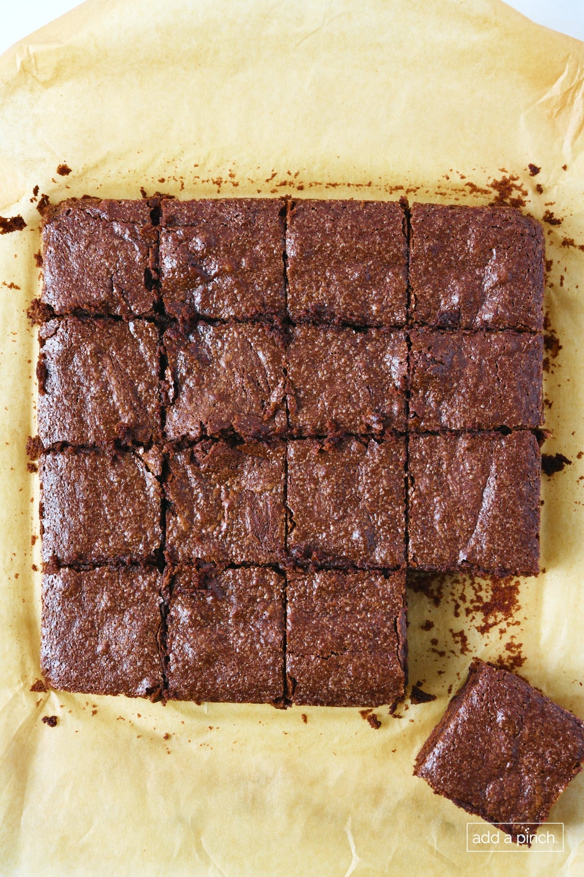 Freshly sliced homemade fudge brownies on parchment, displaying fudgy centers and crackly tops.