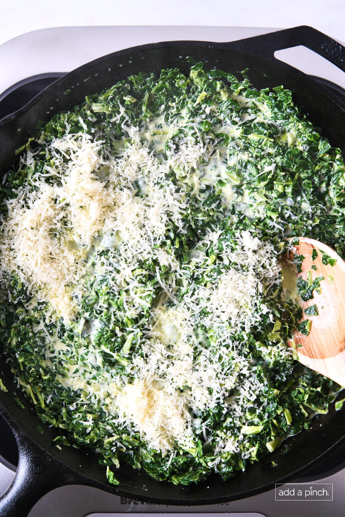Parmesan added to creamed spinach in a skillet.