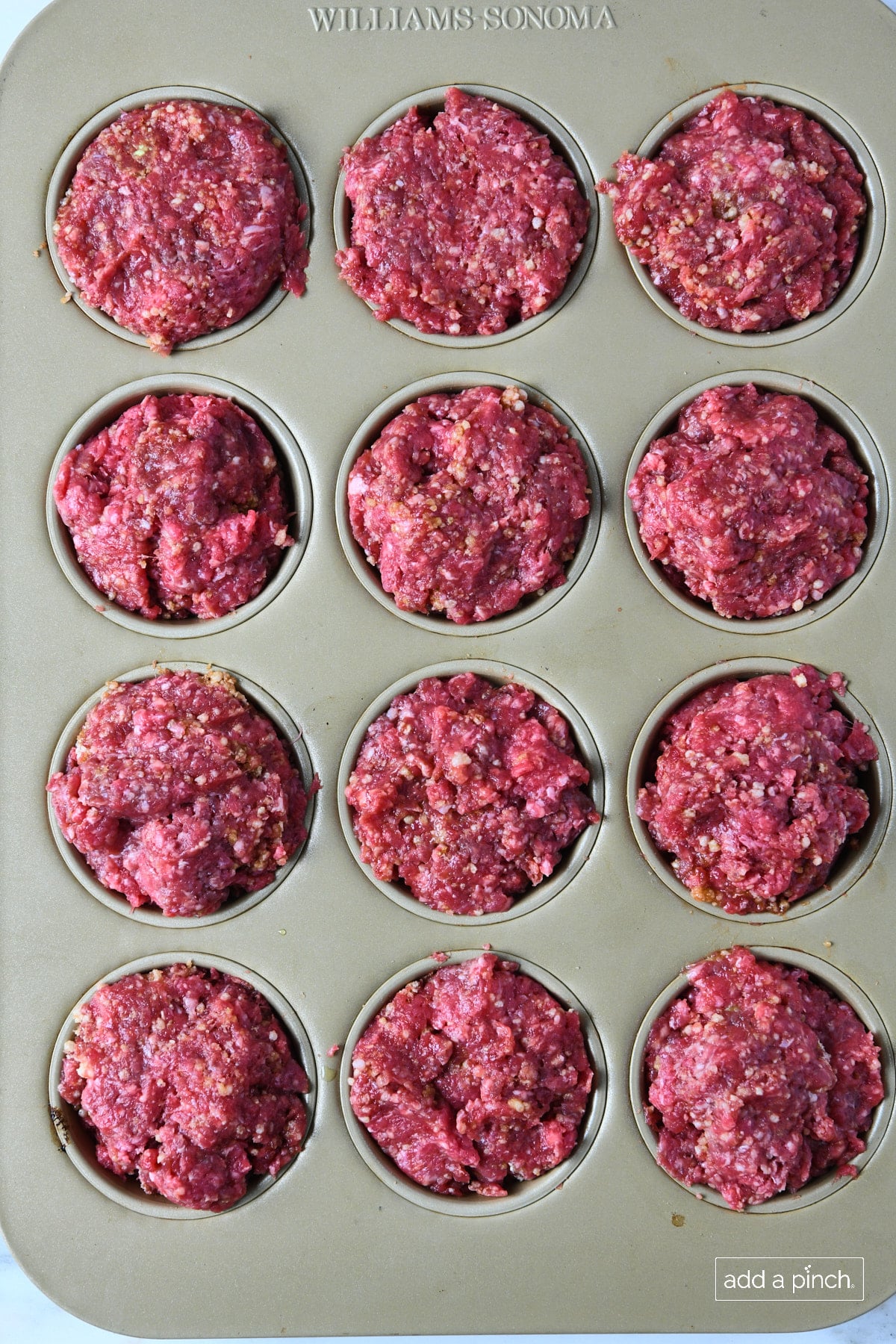 Meatloaf mixture in a muffin pan.