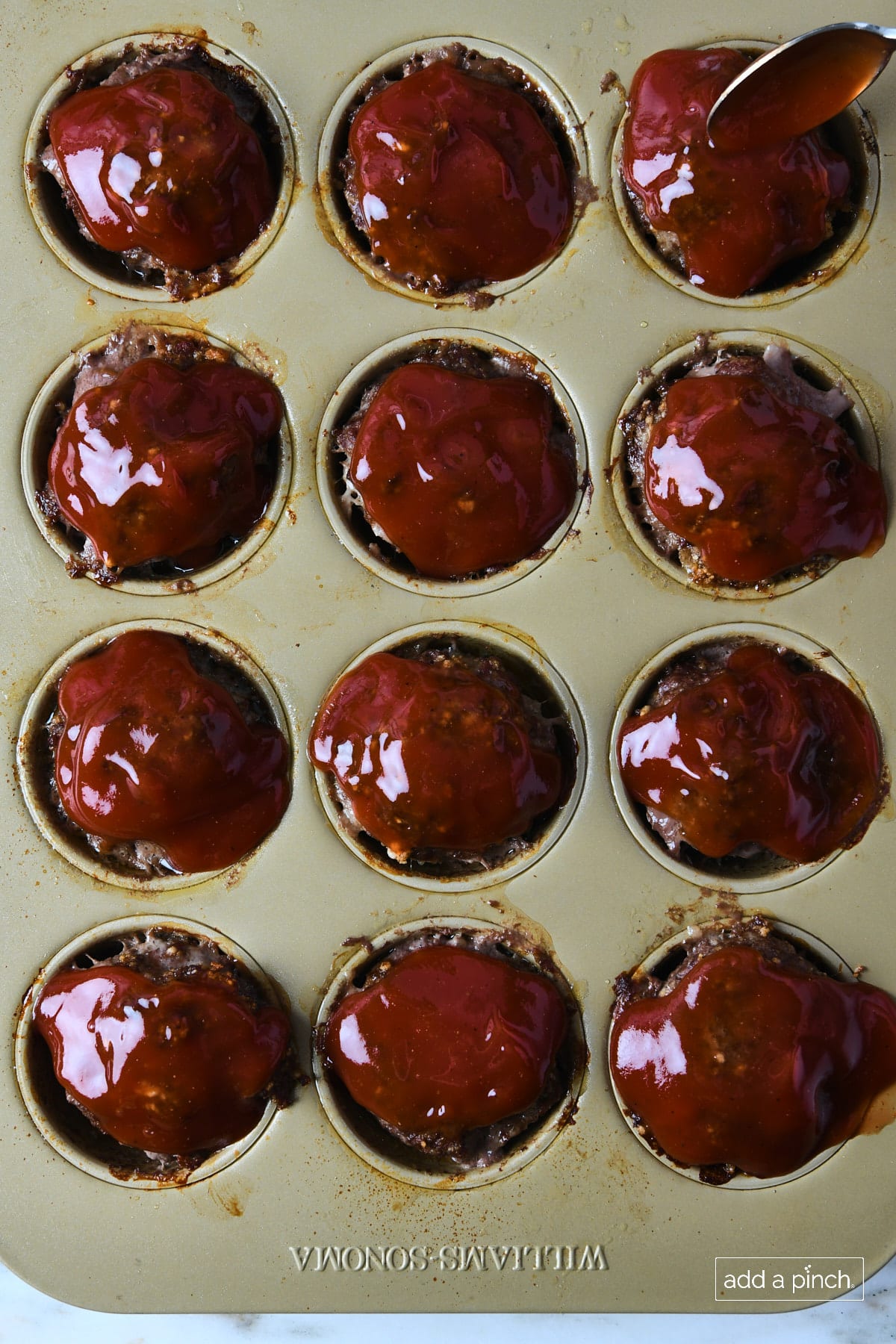 Glazed meatloaf muffins in a muffin pan.
