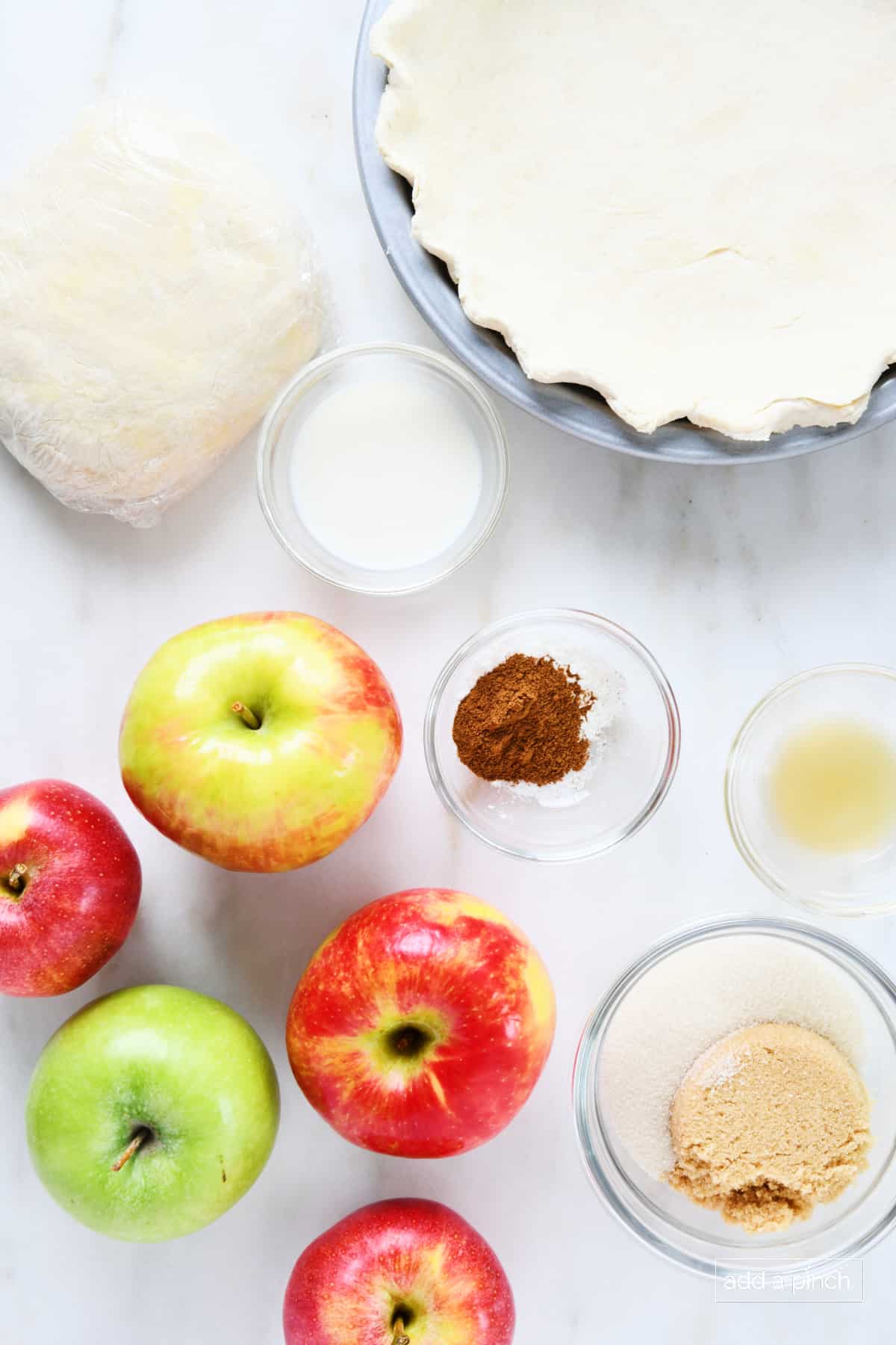 Ingredients used to make homemade apple pie on a marble surface.
